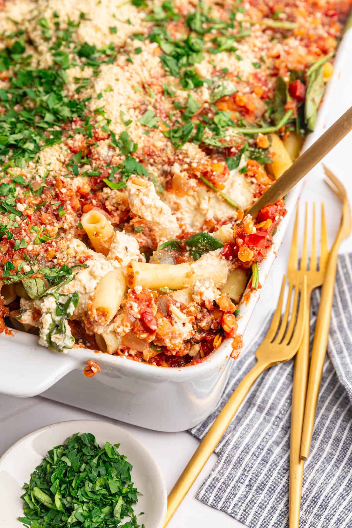 A casserole dish with a serving of vegan baked ziti scooped out.