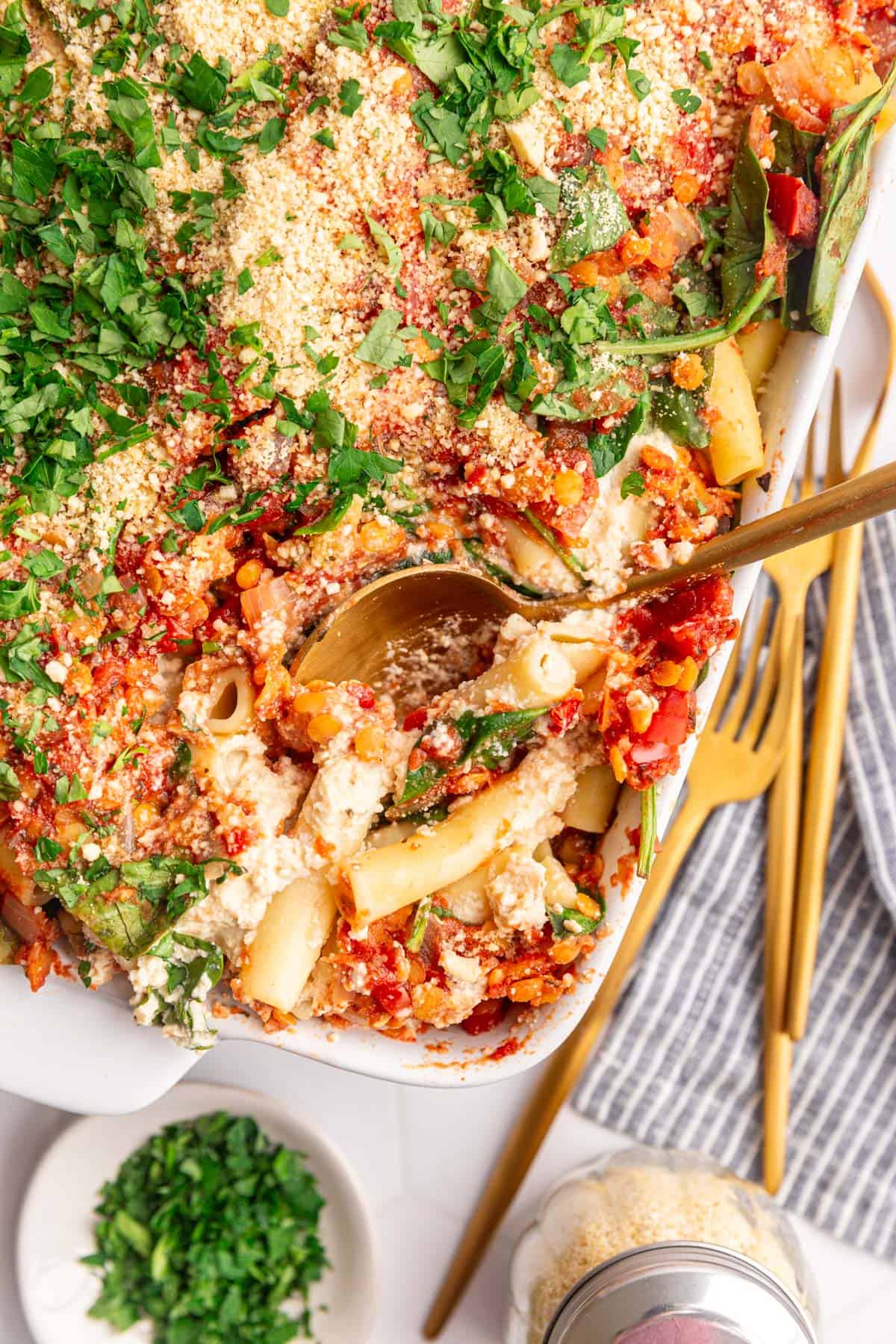 A casserole dish with a serving of vegan baked ziti with ricotta scooped out.