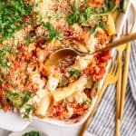 A casserole dish with a serving of vegan baked ziti with ricotta scooped out.