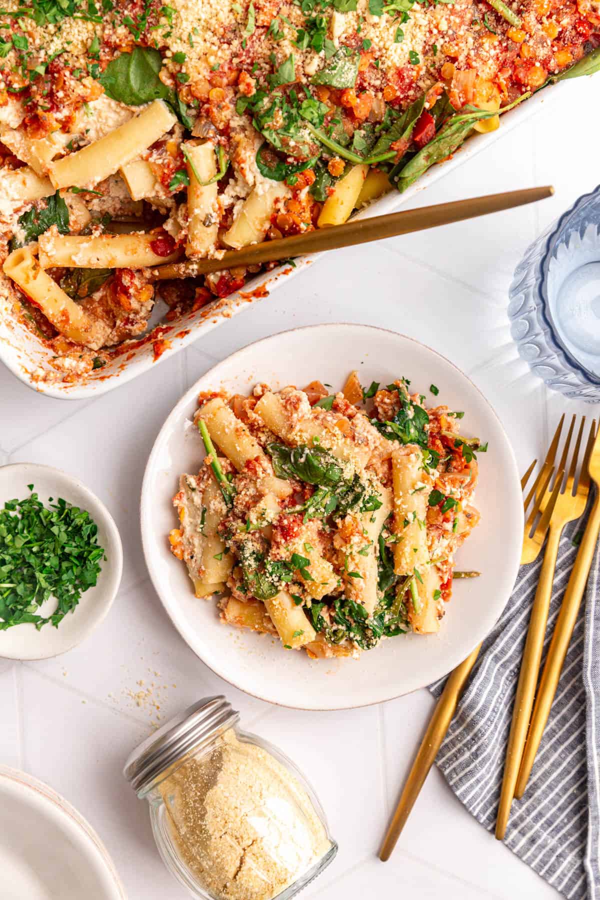 A plate of Vegan Baked Ziti with ricotta, next to the casserole dish.