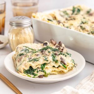 A freshly baked dish of vegan white lasagna, and a plate with a square.
