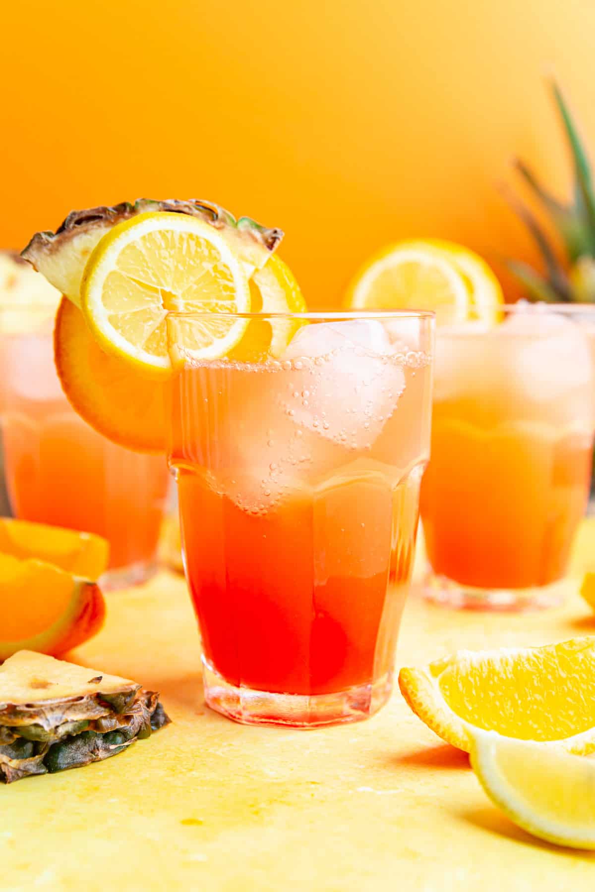 A glass of cinderella mocktail garnished with lemon, orange, and pineapple slices.