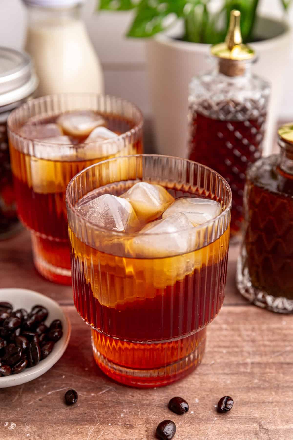 A glass of decaf cold brew on a table with coffee syrups.