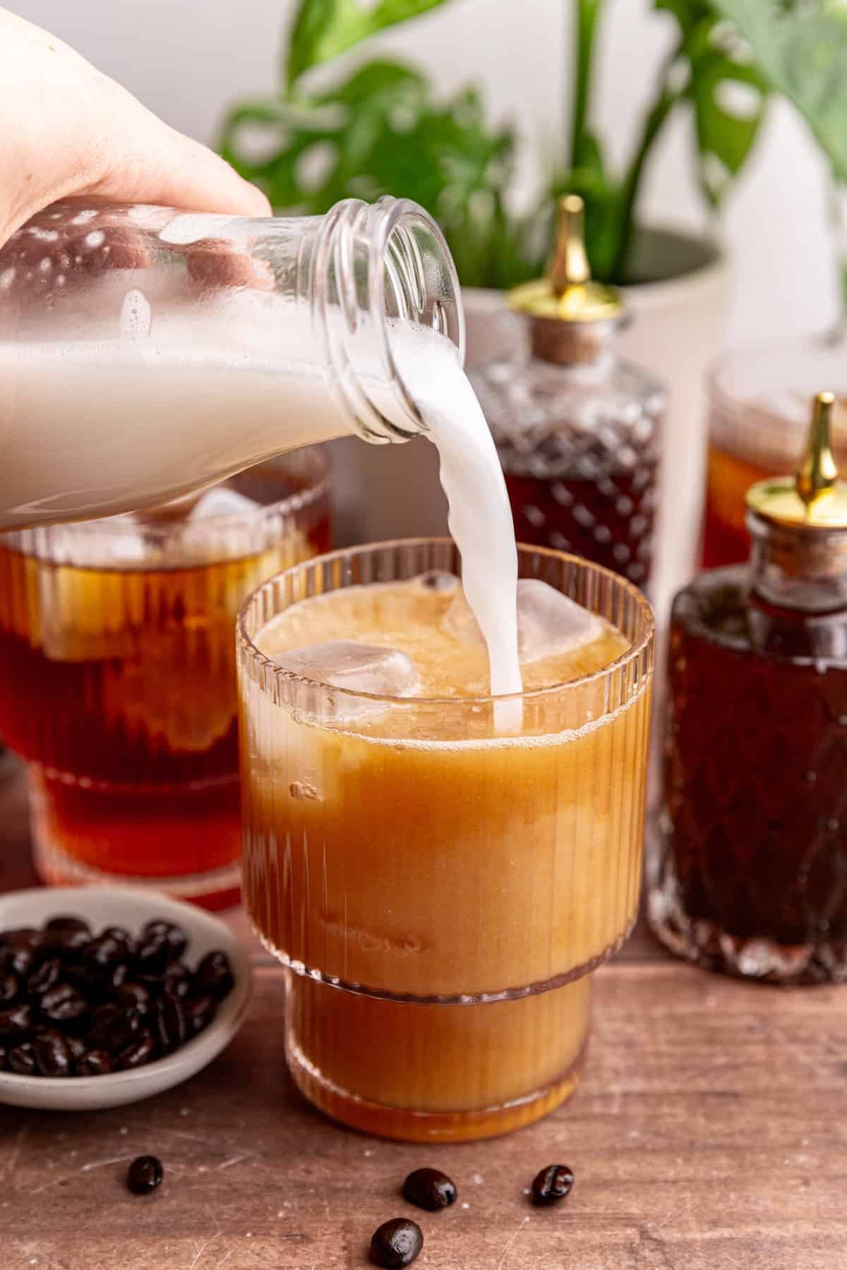 Milk being poured into a glass of cold brew.