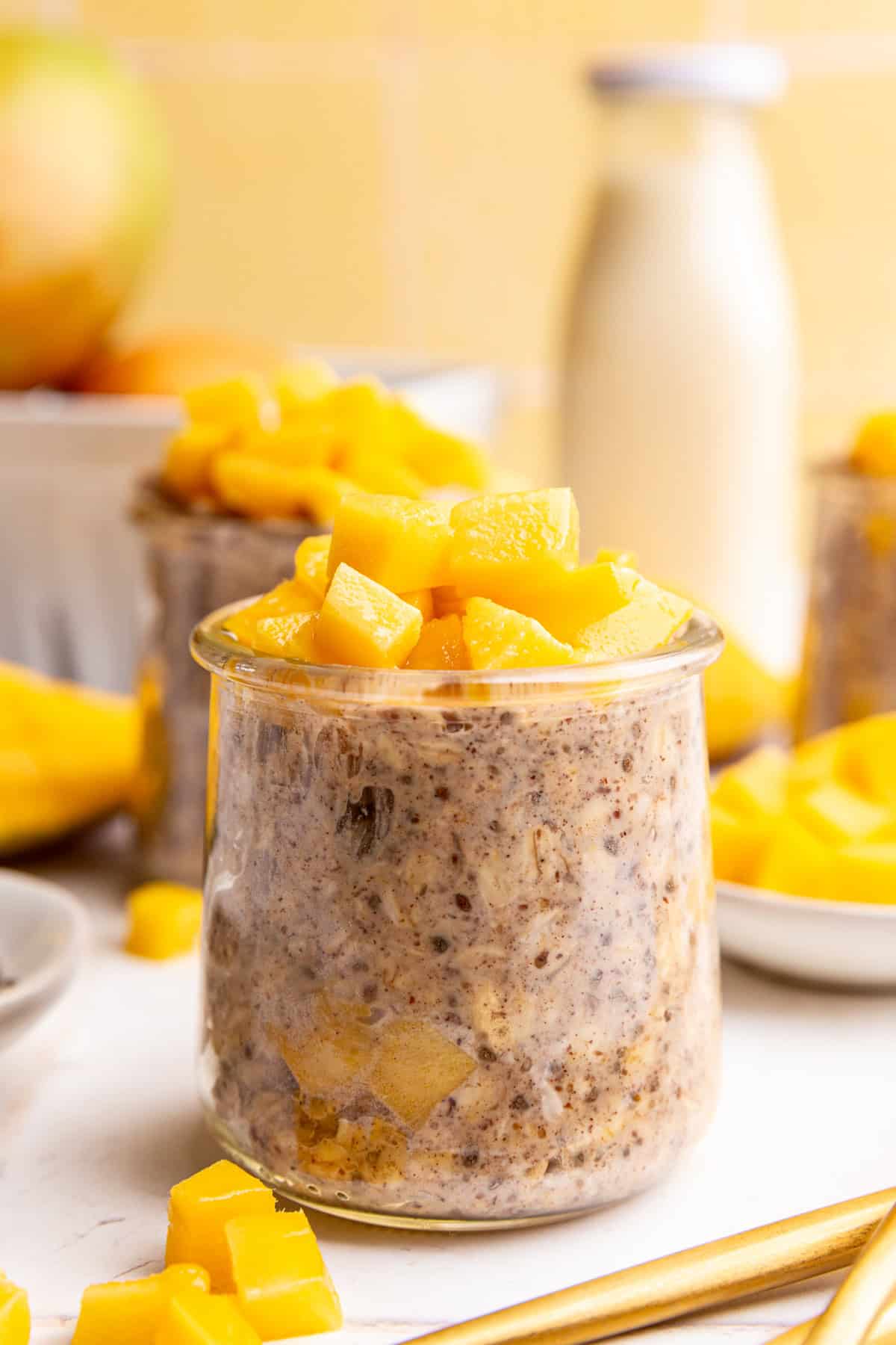 A jar of vegan mango overnight oats, topped with fresh mango chunks.