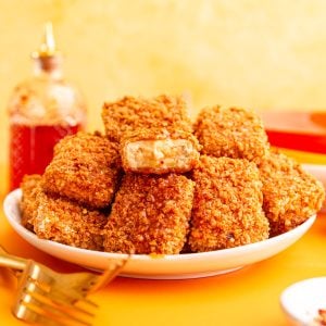 A plate of vegan hot honey tofu, with a piece that was ripped in half.