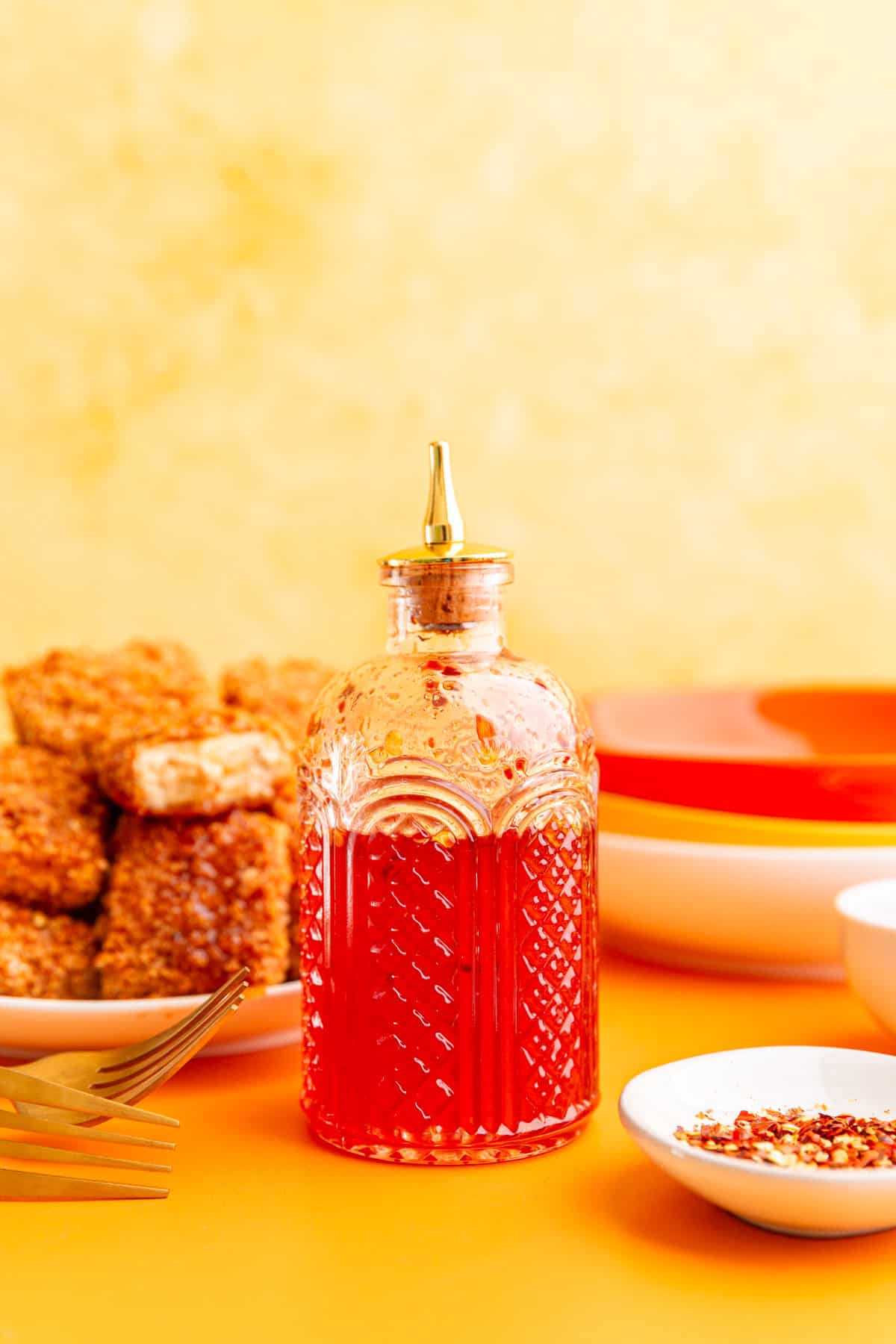 A jar of vegan hot honey with a plate of hot honey tofu.