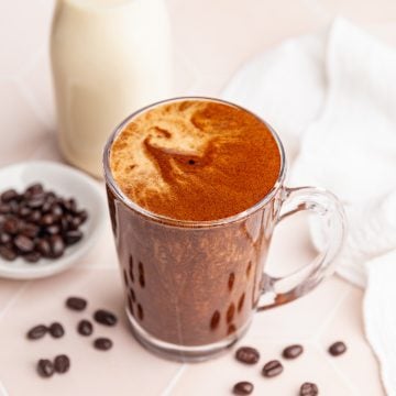 A mug of Vegan Protein Coffee with a bottle of milk.