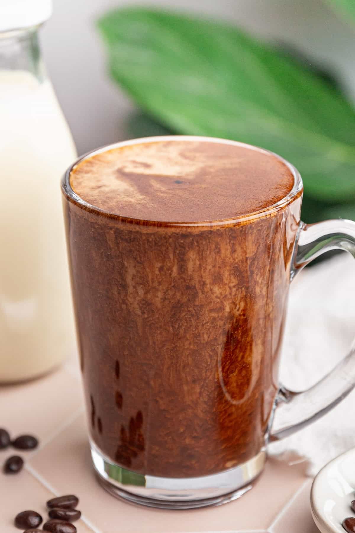 A mug of vegan protein coffee, with a glass of milk.