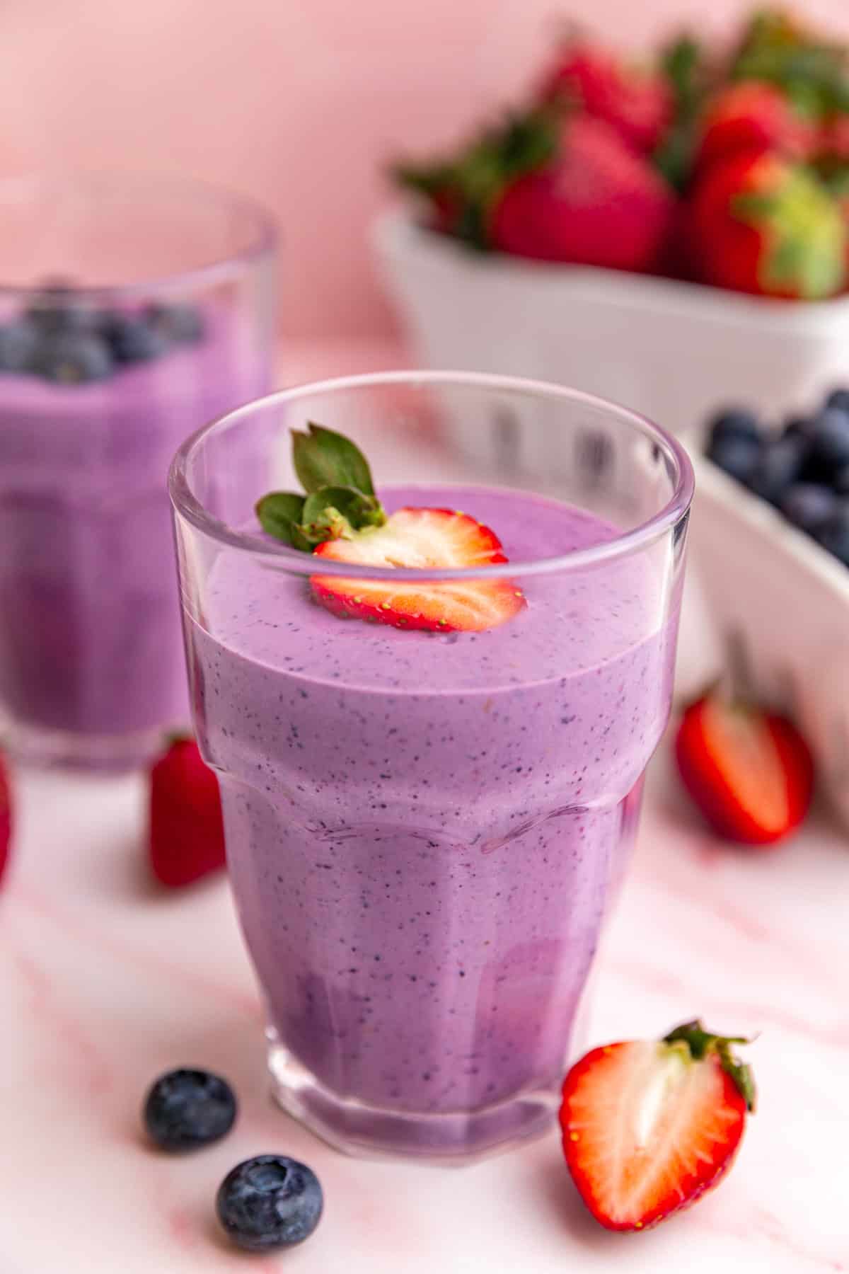 A glass of vegan protein smoothie, garnished with a strawberry.