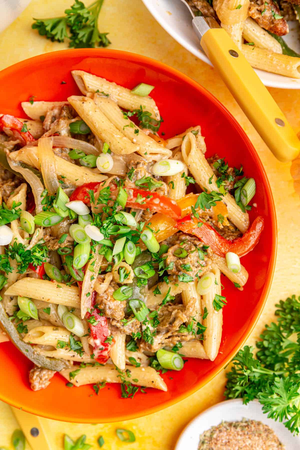 A bowl of vegan rasta pasta, topped with parsley and scallions.