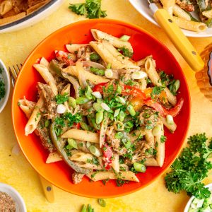 A bowl of vegan rasta pasta, topped with parsley and scallions, ready to eat.