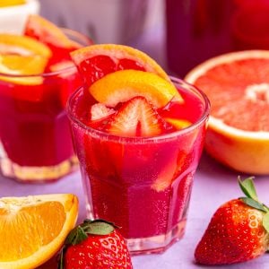 A glass of easter mocktail, garnished with strawberries, oranges, and grapefruits.