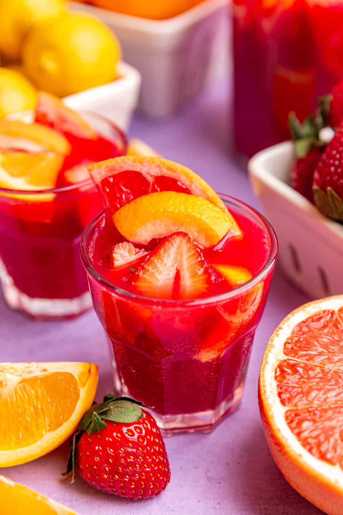 A glass of easter mocktail, garnished with strawberries, oranges, and grapefruits.