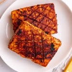 Two pieces of glazed tofu ham on a plate.