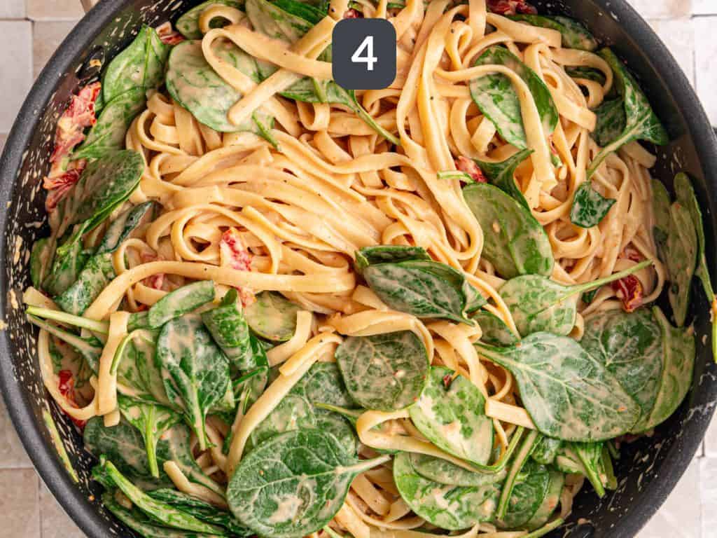 Vegan sundried tomato pasta step 4 - toss in the pasta and spinach.