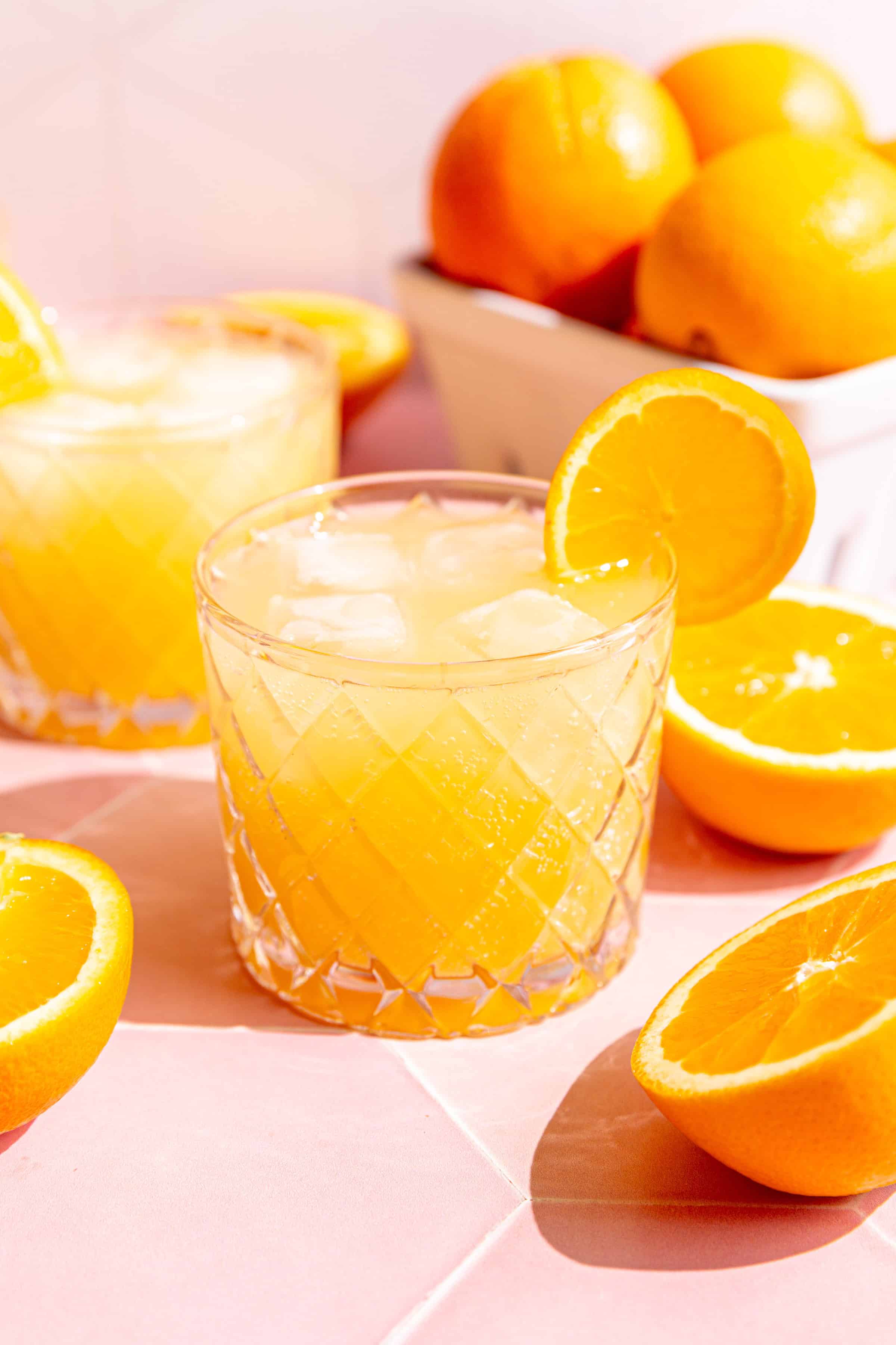 A glass of aperol spritz, surrounded by fresh oranges.