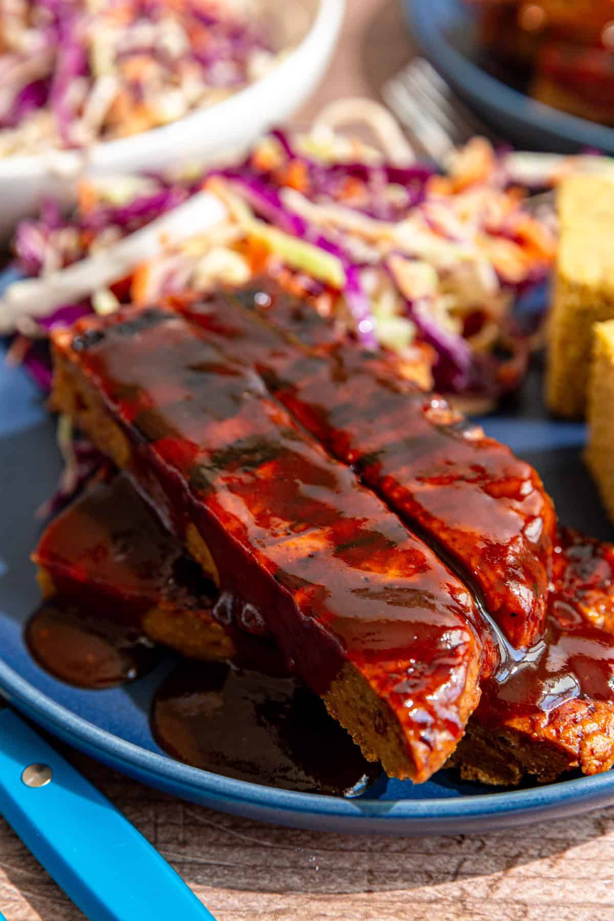 A plate of bbq seitan ribs, cornbread, and coleslaw.