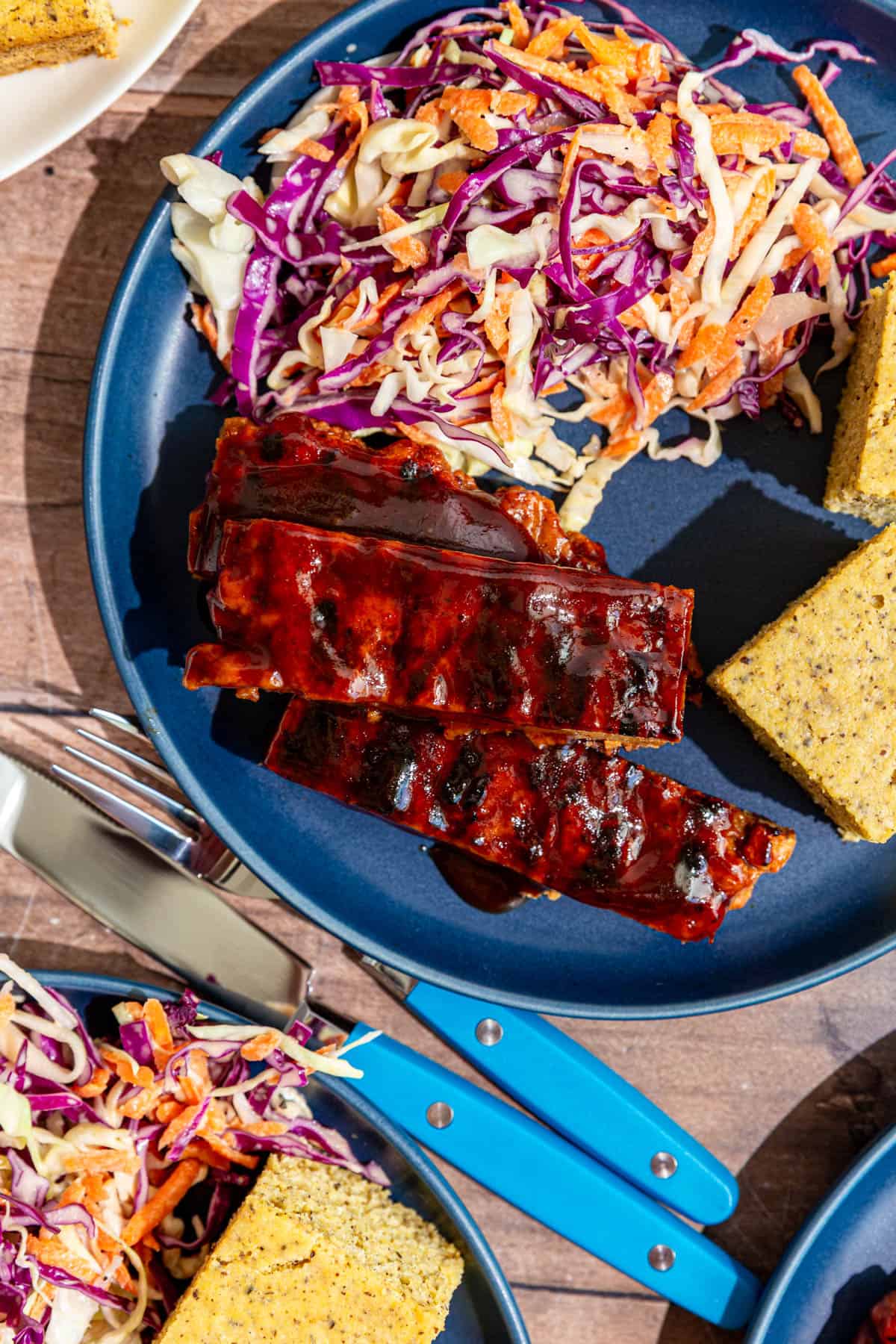 Several plates of ribs, cornbread, and coleslaw.