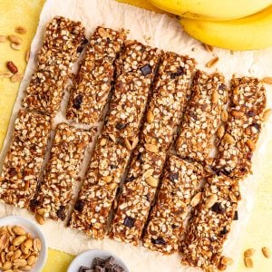 A batch of banana granola bars, on a piece of parchment paper, sliced and ready to eat.