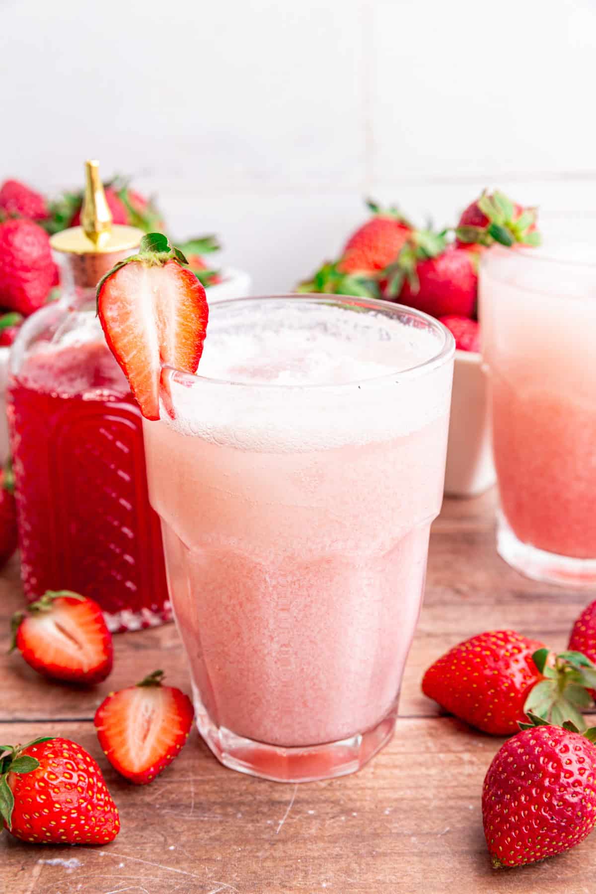 A glass of strawberry cream soda, with a strawberry for garnish.