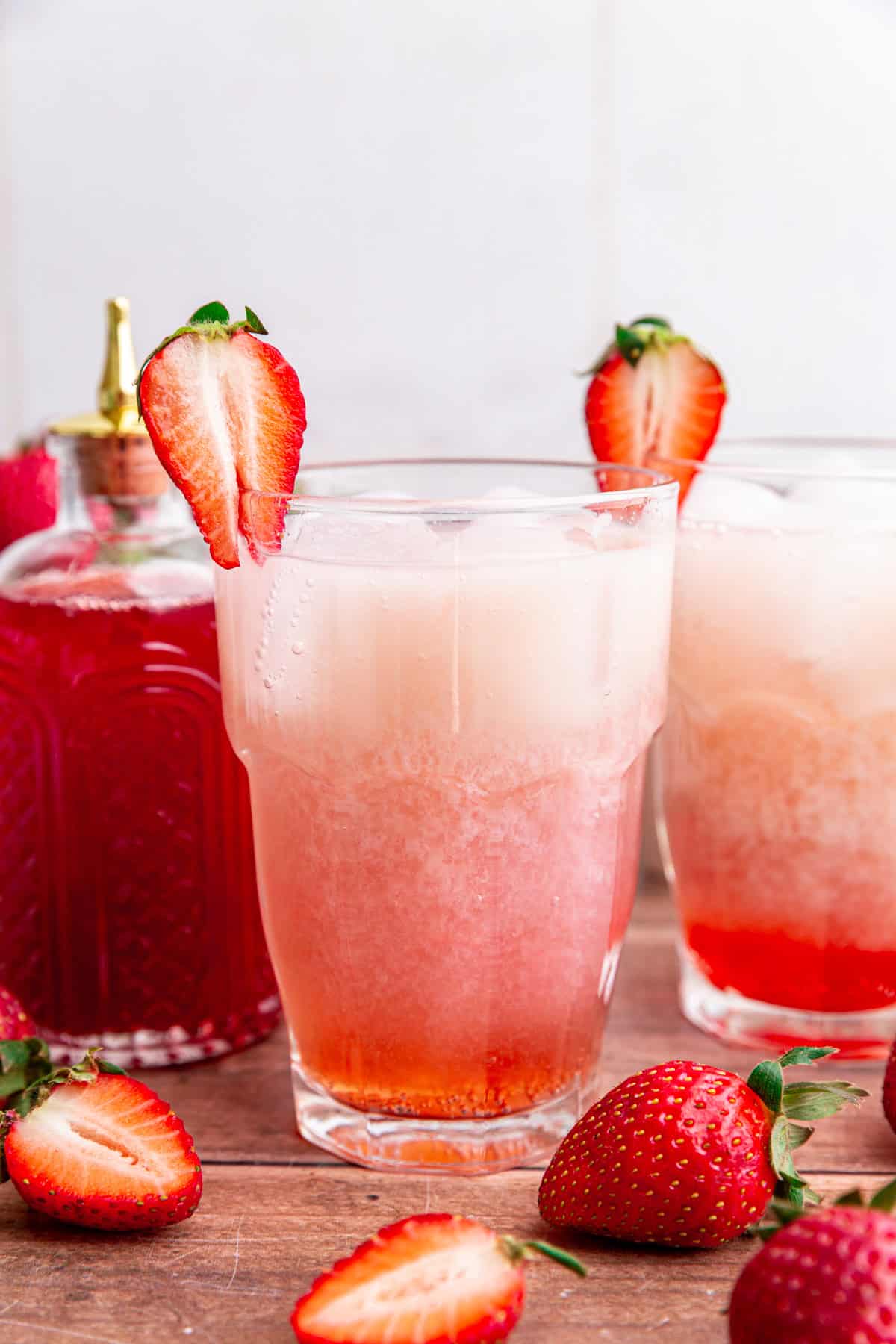 Two glasses of strawberry cream soda, with a strawberry for garnish.