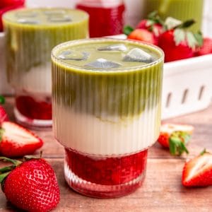 A glass of strawberry matcha latte, with three distinct layers of red syrup, white milk, and green matcha.