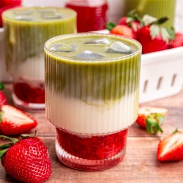 A glass of strawberry matcha latte, with three distinct layers of red syrup, white milk, and green matcha.