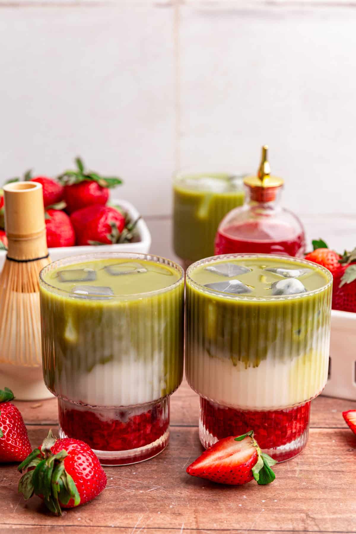 Two iced strawberry matcha lattes on a table.