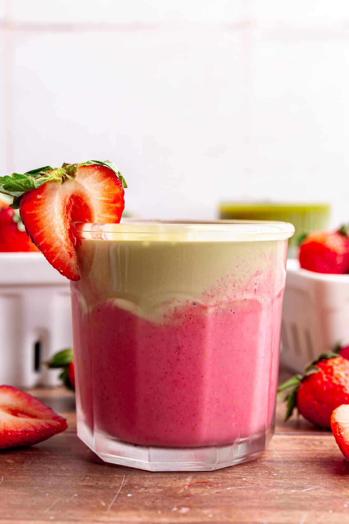 A strawberry matcha smoothie, garnished with a fresh strawberry.