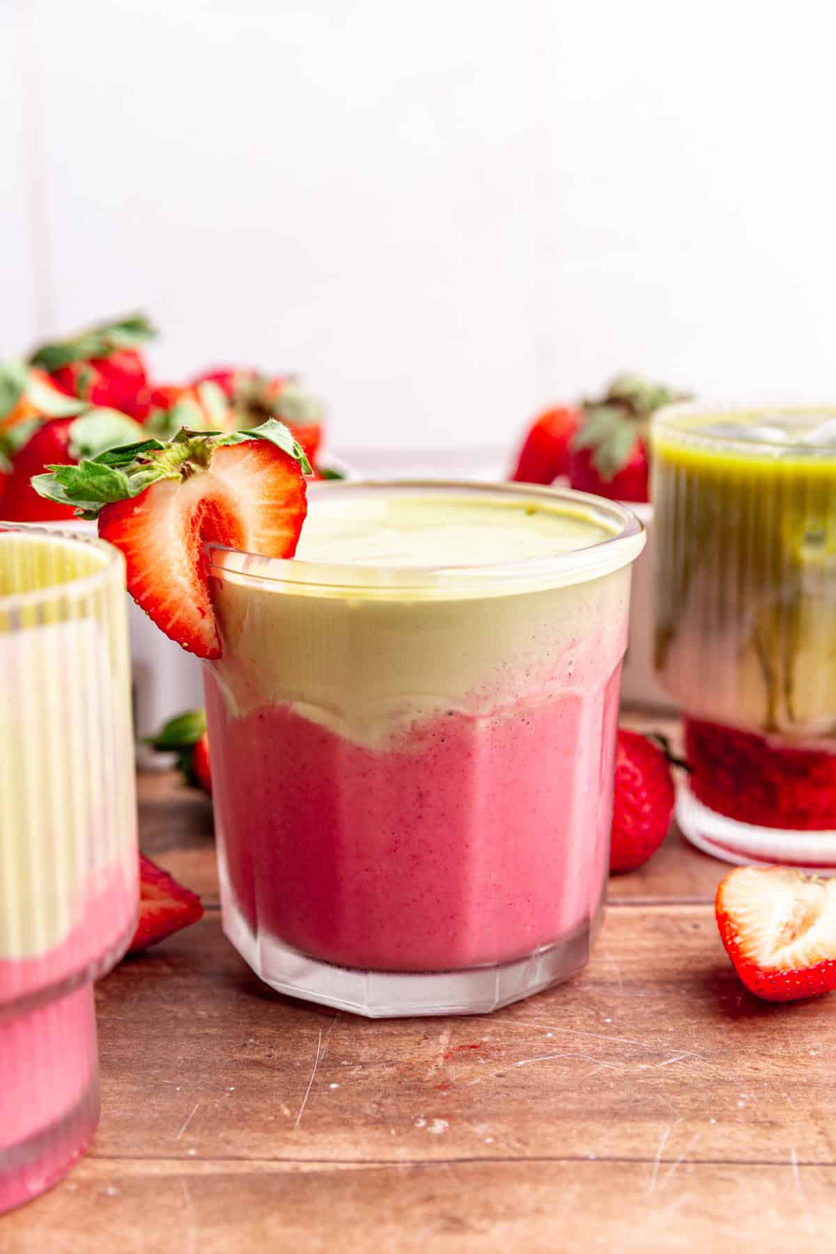 A strawberry matcha smoothie, garnished with a fresh strawberry.