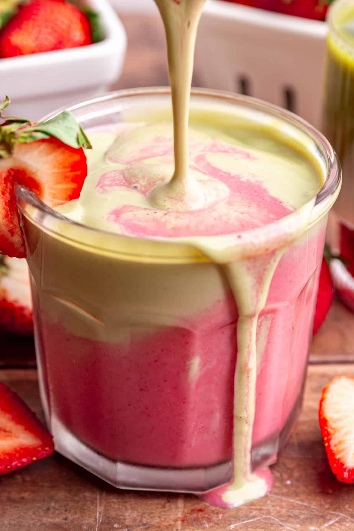 Matcha layer being poured into a glass of smoothie.