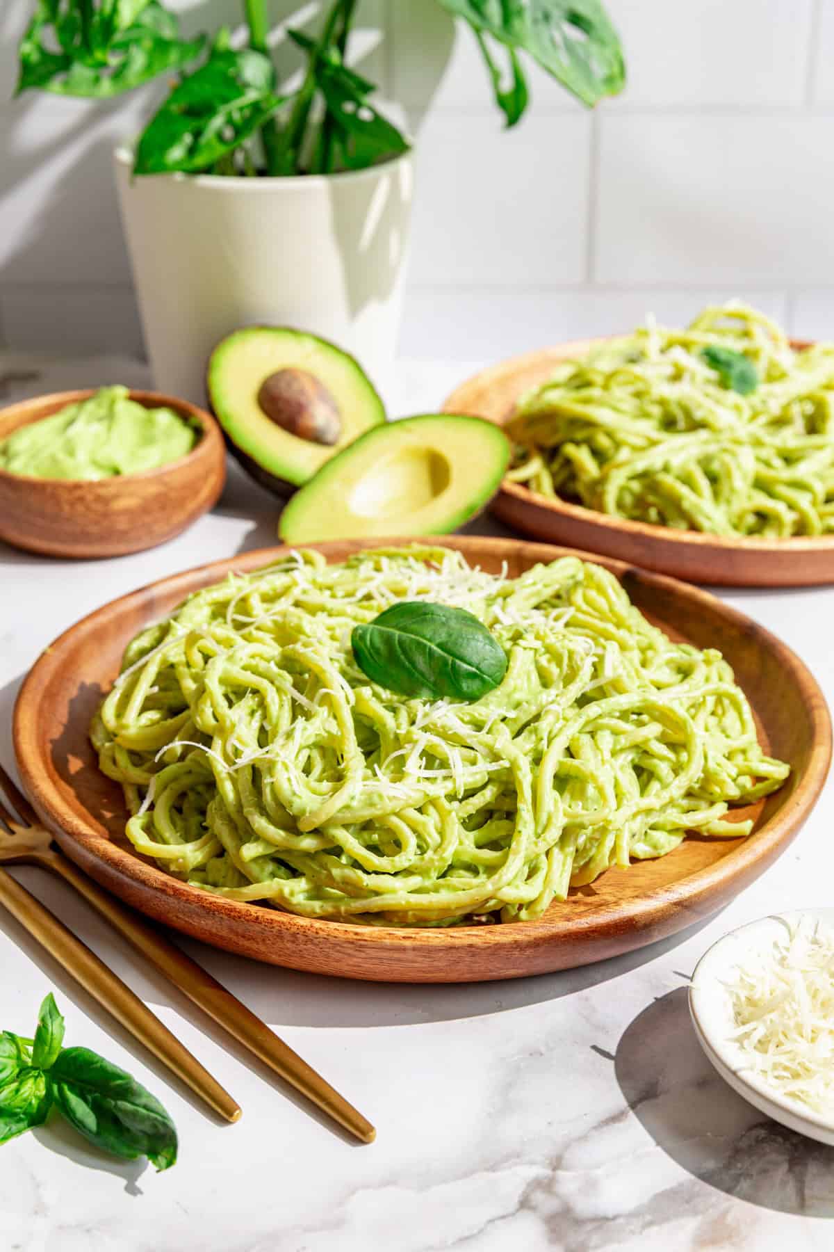 A plate of vegan avocado pasta garnished with vegan parmesan and fresh basil.