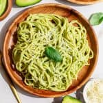 A plate of vegan avocado pasta garnished with vegan parmesan and fresh basil.