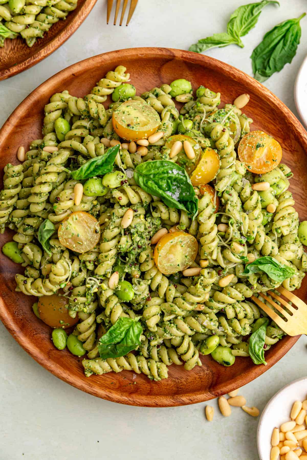 A plate of creamy vegan pesto pasta salad, with a fork, ready to eat.