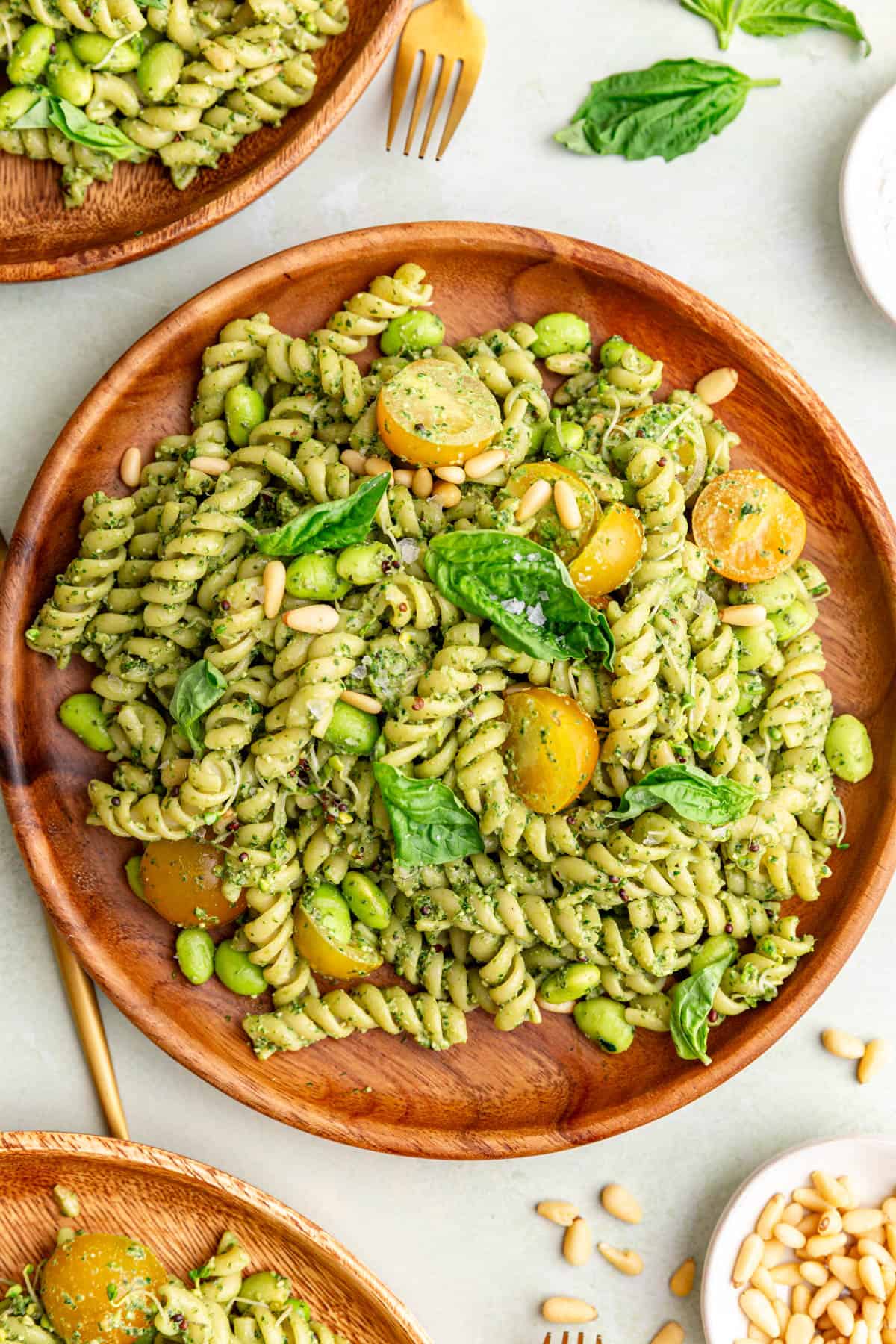 A plate of creamy vegan pesto pasta salad, garnished with fresh basil.