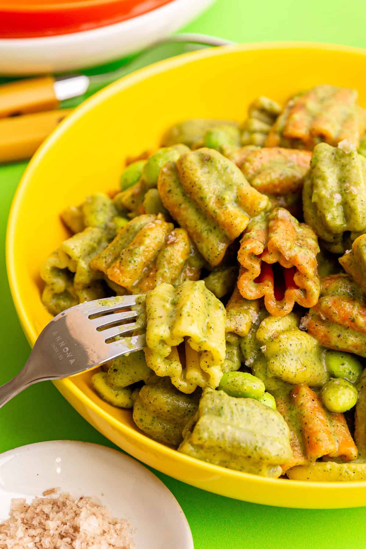 A bowl of vegan zucchini pasta, with a fork taking a piece of pasta away.