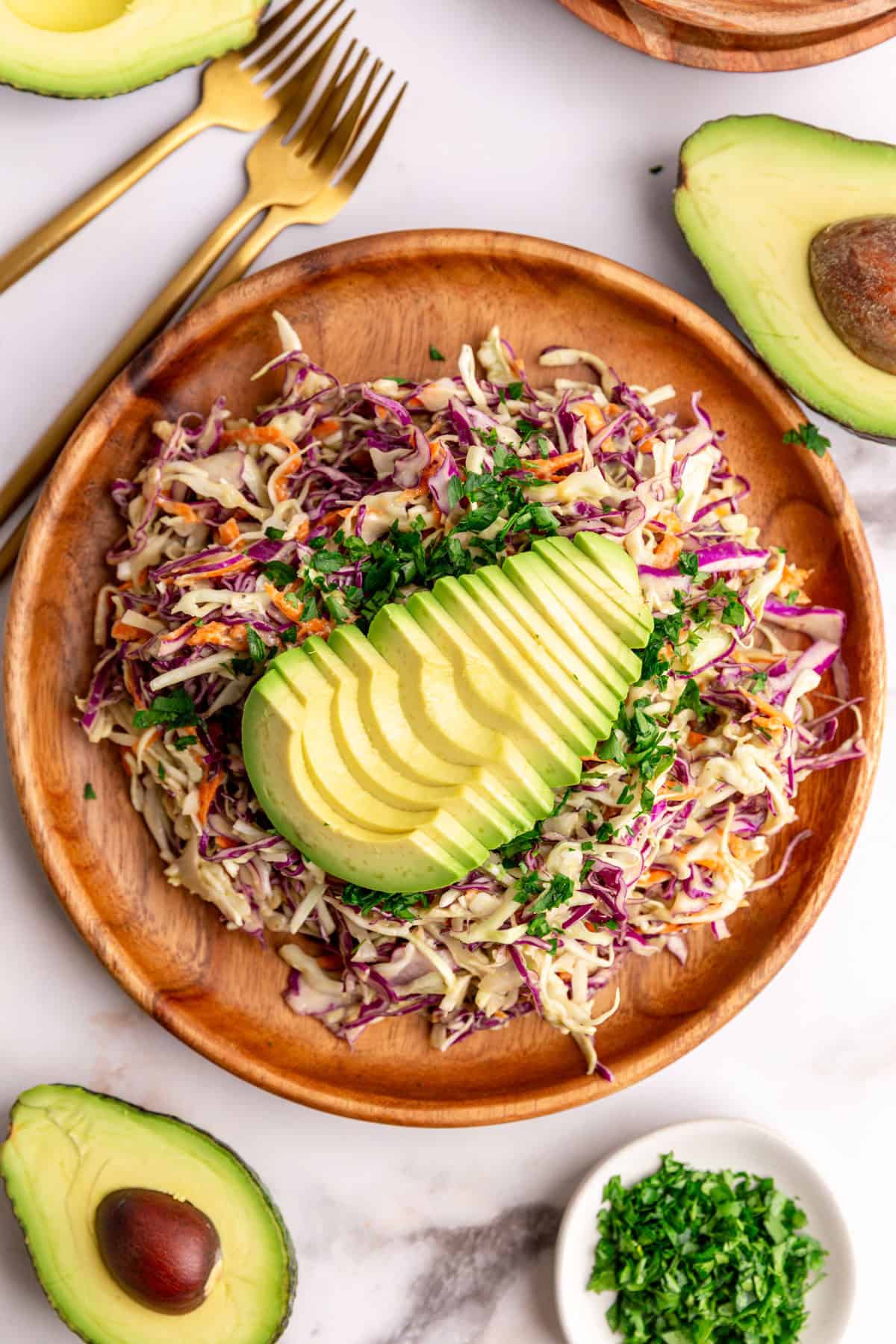A plate of avocado slaw garnished with a sliced avocado.