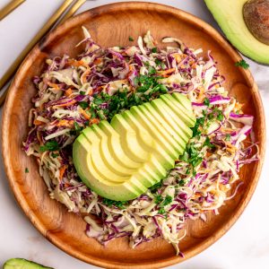 A plate of avocado slaw garnished with a sliced avocado.