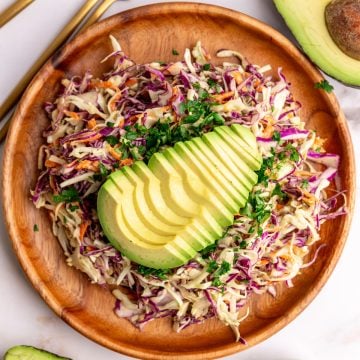 A plate of avocado slaw garnished with a sliced avocado.