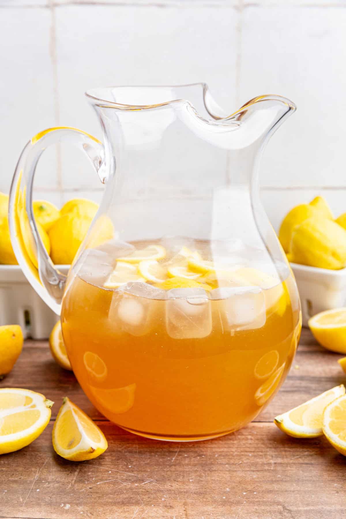 A pitcher of brown sugar lemonade surrounded by fresh lemons.