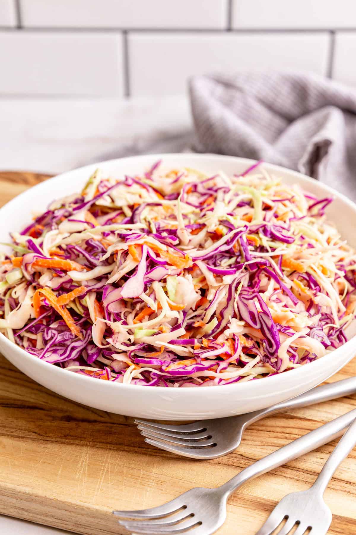 A bowl of vegan coleslaw on a cutting board