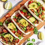 A cutting board lined with vegan chicken tacos.
