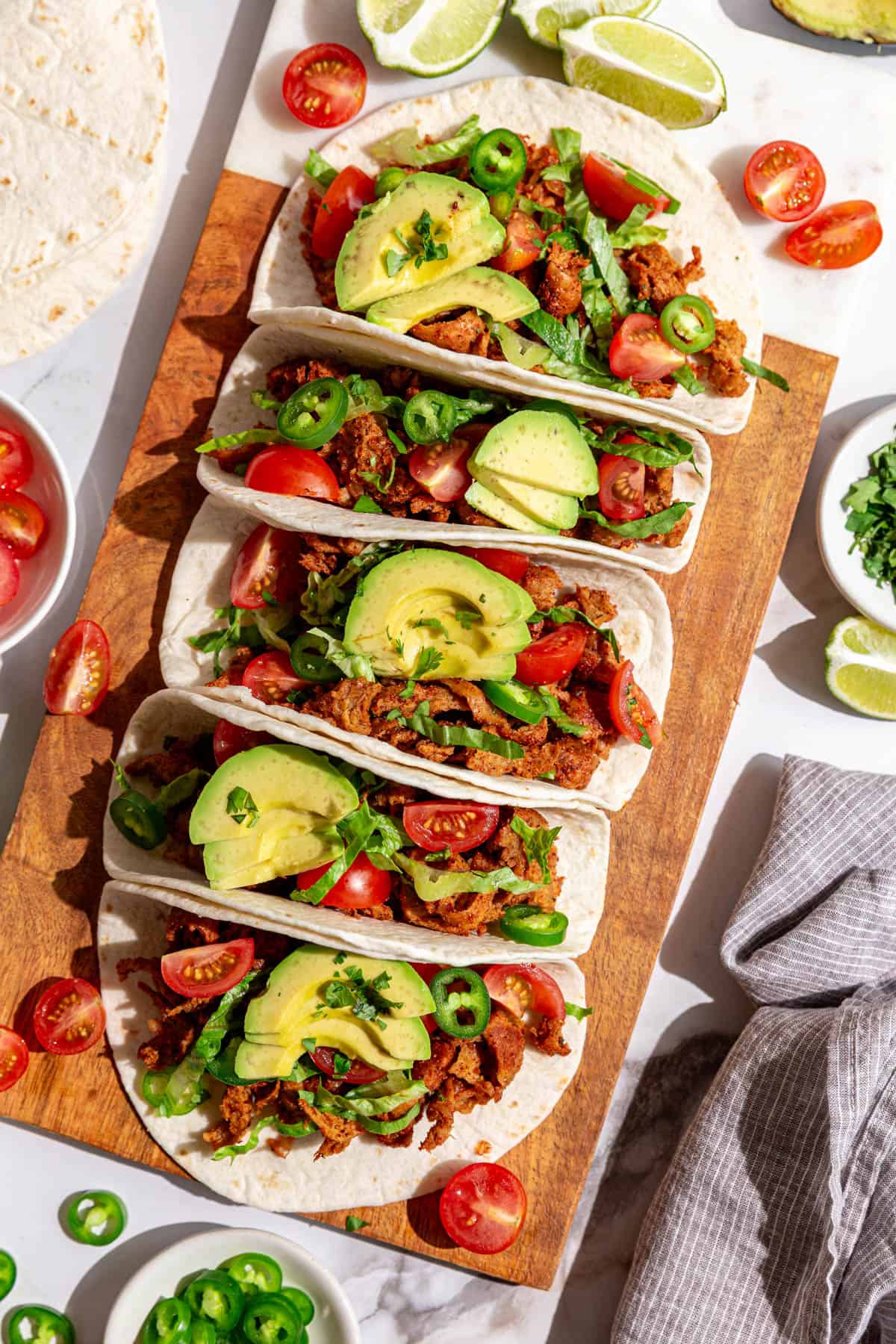A cutting board with several vegan chicken tacos.