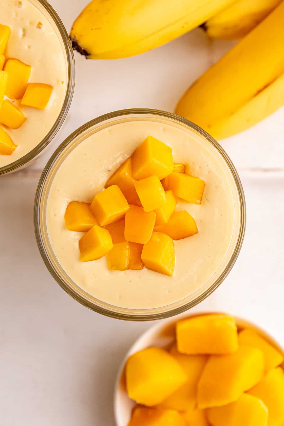 A top down view of a thick mango smoothie topped with mango chunks.