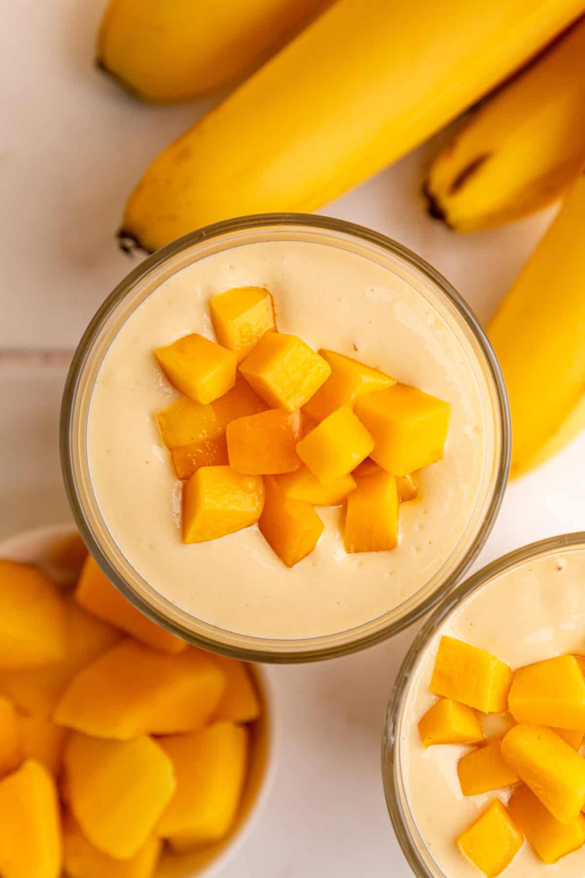 A top down view of a thick mango smoothie topped with mango chunks.