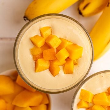 A top down view of a thick mango smoothie topped with mango chunks.
