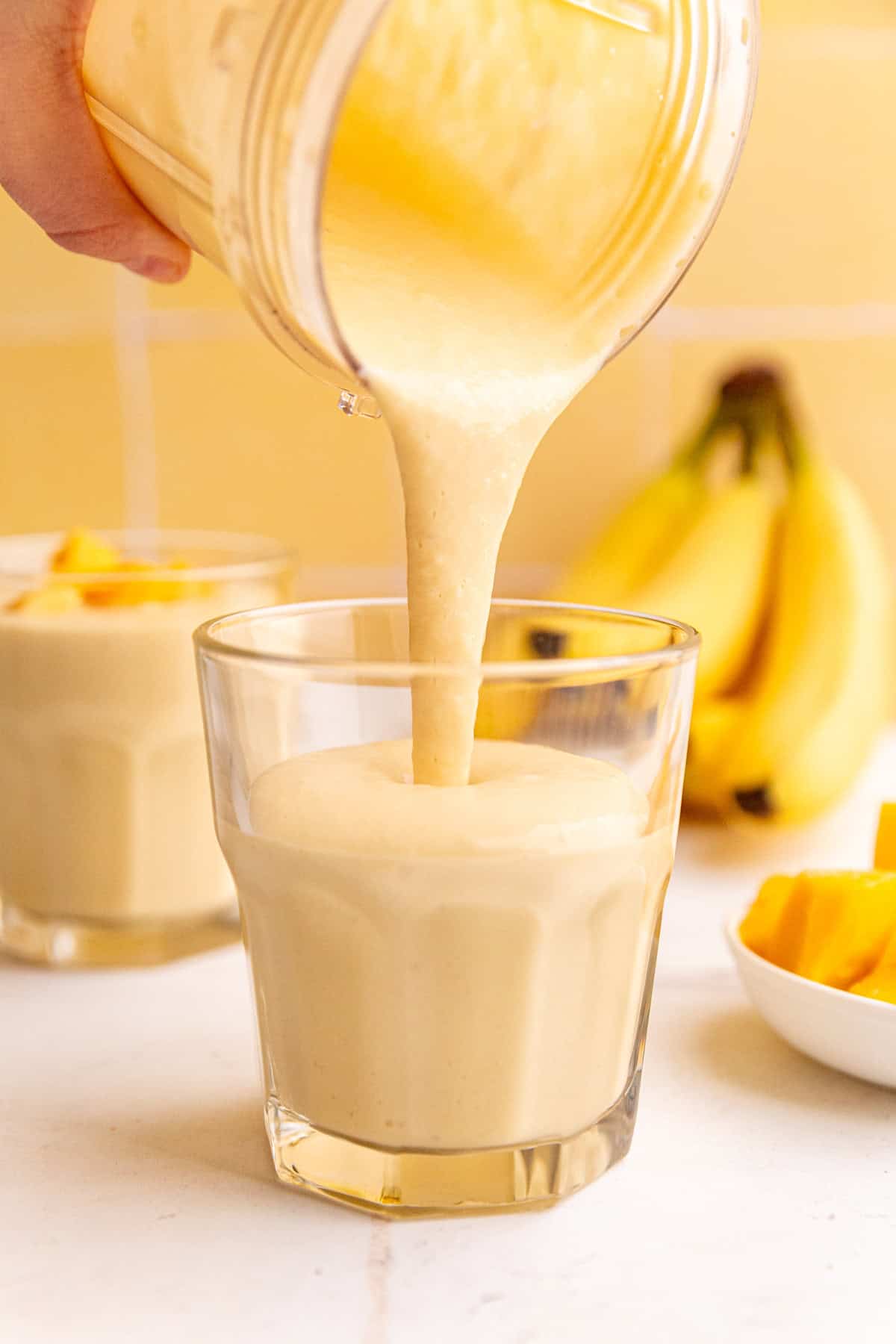 A mango smoothie poured from the blender into a glass.