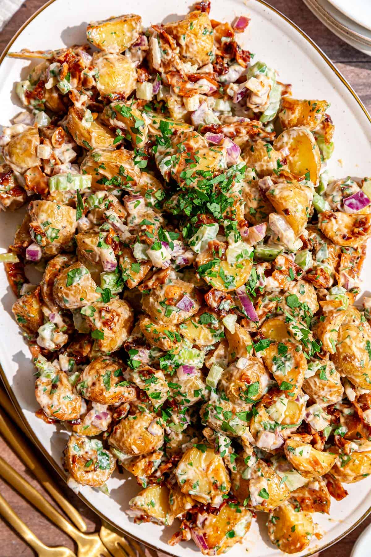 A platter of vegan roasted potato salad, garnished with extra parsley.