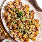 A platter of vegan roasted potato salad, garnished with extra parsley.